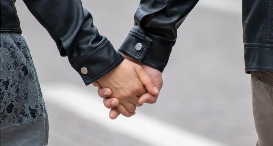 Einfluss der Persönlichkeit auf eine Partnerschaft während einer Pandemie. Man sieht zwei Hände, die sich gegenseitig halten, vermutlich von einem Paar.